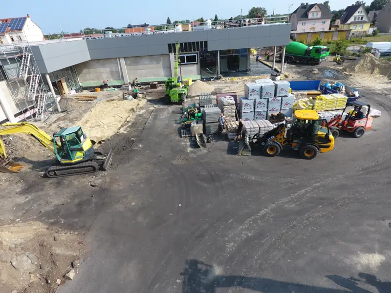 Bagger und Radlader beim Bau eines Parkplatzes an einem Gewerbebau