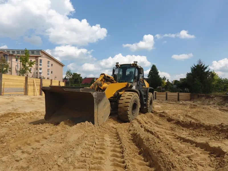 Radlader beim Erdbau auf sandigem Boden in einer Baugrube