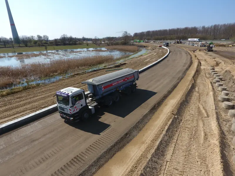 Kipper-Lkw auf einer neuen Tragschicht beim Straßenbau